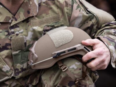 Camouflaged user holding Armor Source ballistic Helmet