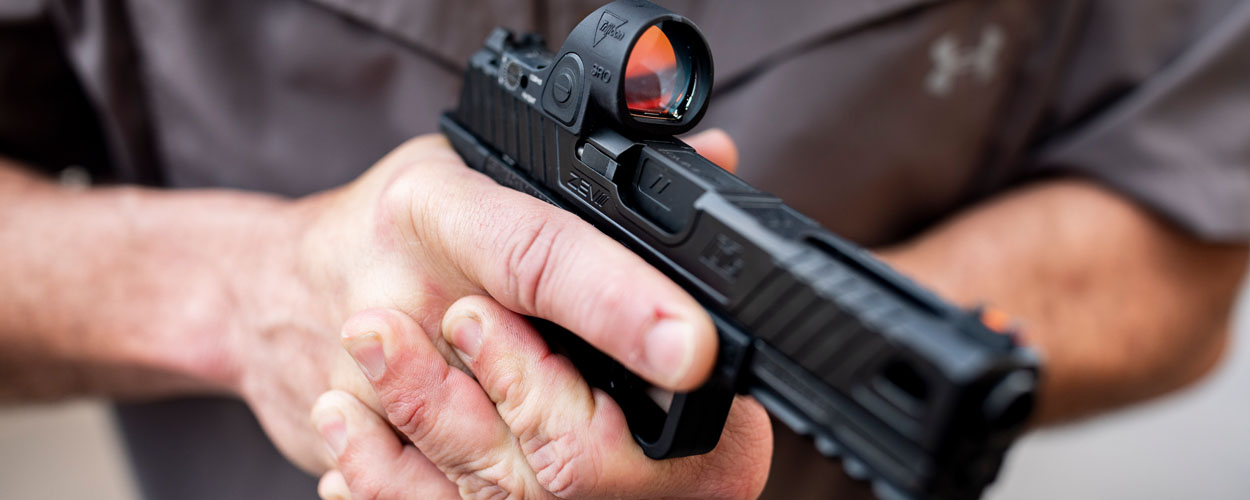 Trijicon SRO mounted on pistol being held by opertaive